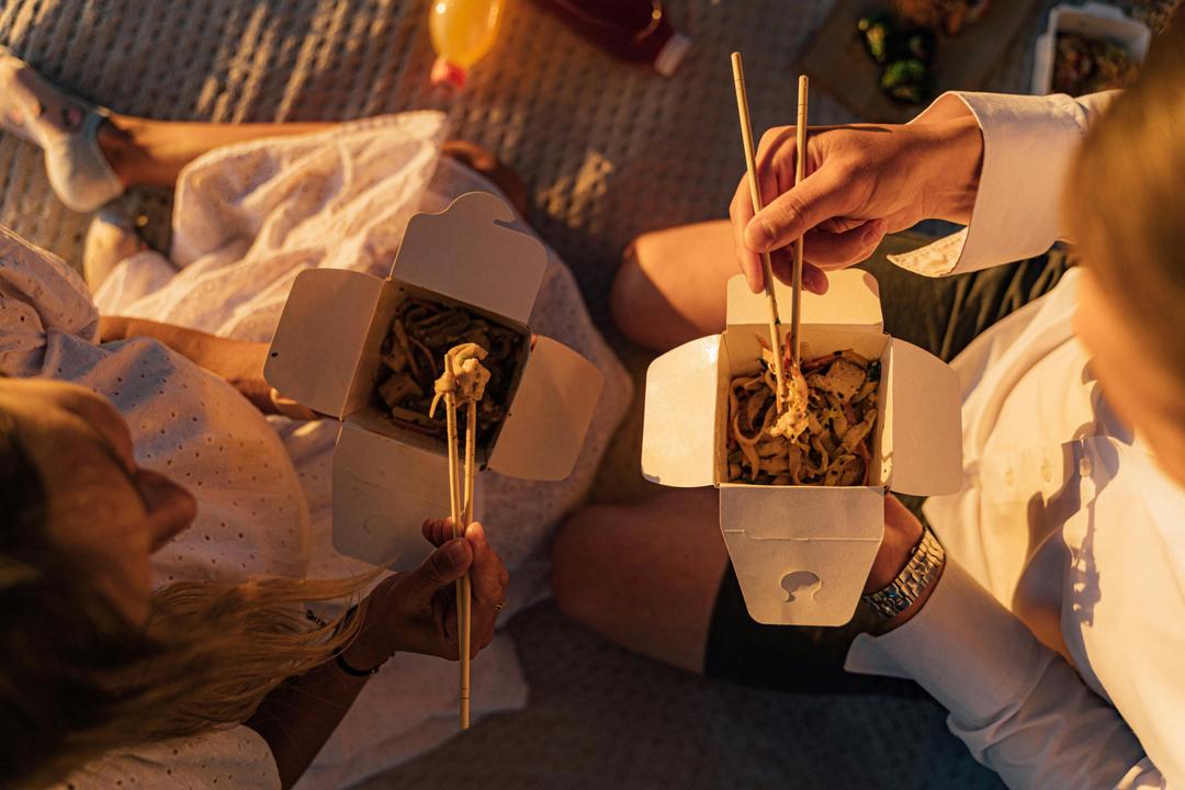 People eating takeaway food from packaging boxes